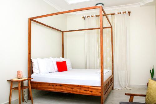 Kiembi SamakiKwale Residence的一间卧室配有一张带红色枕头的木天蓬床