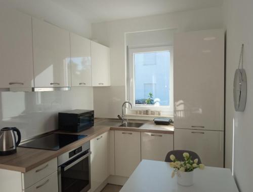 佩特坎内Apartman Punta Radman的厨房配有白色橱柜、水槽和窗户。