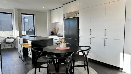 皇后镇Homestead Retreat - 2 Bedroom - Lake View的厨房配有桌椅和黑冰箱。