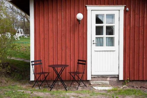 赫尔辛基Seaside Cottage in Suomenlinna的一间红色的房子,门前设有两把椅子和一张桌子