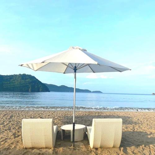 纳苏格布Pico De Loro Room Rental的海滩上的两把椅子和一把遮阳伞