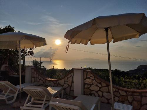 阿纳卡普里Casa Astra的一个带椅子和遮阳伞的庭院,享有日落美景