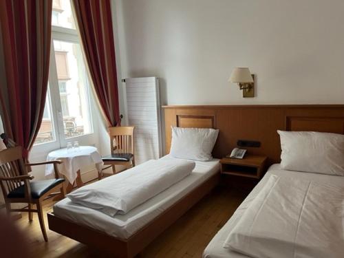 特里尔Hotel Römischer Kaiser的酒店客房设有两张床和窗户。