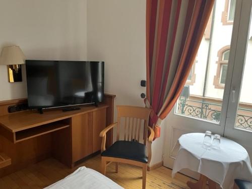 特里尔Hotel Römischer Kaiser的配有电视、椅子和桌子的房间