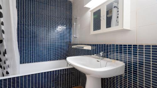 勒格罗-迪鲁瓦Terrasses de l Espiguette 320 - Studio 2 pers的蓝色瓷砖浴室设有水槽和镜子