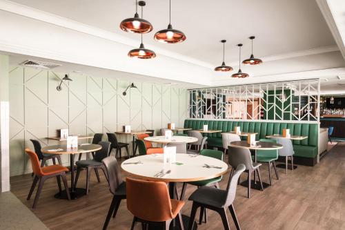 雷丁假日雷丁西区酒店的一间带桌椅和绿色墙壁的餐厅