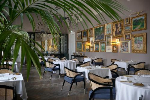 TuraBOTANIQ Castle of Tura - Small Luxury Hotels of the World的餐厅设有白色的桌椅,墙上挂有绘画作品
