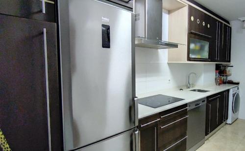 桑托尼亚APARTAMENTO 2 HABITACIÓNES con GARAJE EN SANTOÑA的厨房配有不锈钢冰箱和水槽