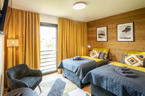 Veľká TŕňaUbytovanie na Tokaji Empora Apartman的一间卧室设有两张床、一把椅子和一个窗户。