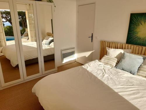 滨海卡瓦莱尔4-Star Private Villa with Heated Pool and Panoramic Sea View at Gulf de Saint Tropez的卧室配有白色的床和镜子