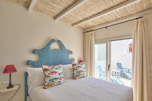 塔里法El Escondite Tarifa的一间卧室配有一张带蓝色床头板的床和窗户