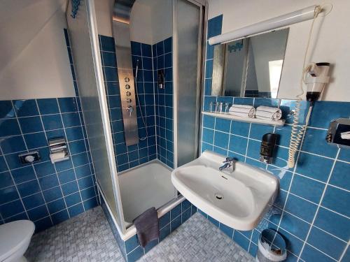 FedderwardersielHotel Zur Fischerklause的蓝色瓷砖浴室设有水槽和淋浴
