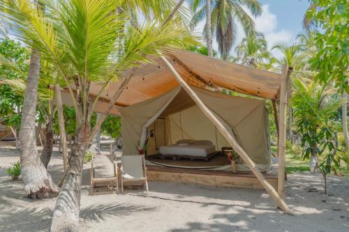 伯里塔卡Manoush Beach的海滩上的帐篷,配有床和棕榈树