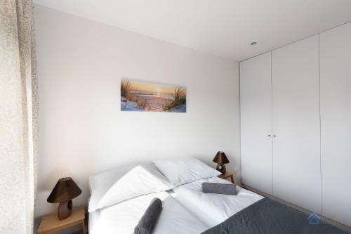 格丁尼亚Uroda Morza by 3City Rentals的白色卧室配有一张床,墙上挂着一幅画