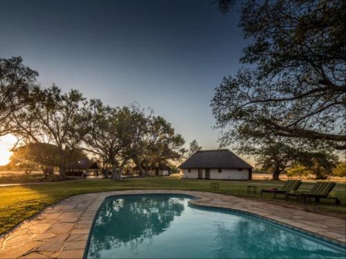 楚梅布La Rochelle Lodge Namibia Tsumeb的一座位于庭院内的游泳池,其建筑背景为: