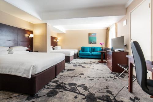 伦敦丹乌比斯摄政公园酒店的酒店客房,设有两张床和一张蓝色的沙发