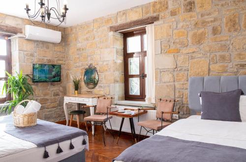 格克切达镇Salkım Otel Gökçeada的一间卧室配有两张床、一张桌子和一张书桌
