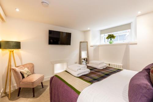 爱丁堡RÌGH Properties - Luxury West End Artisan Apartment的一间卧室配有一张床、一把椅子和电视。