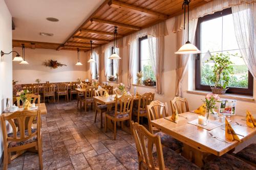Lengefeld瓦尔德斯鲁酒店的餐厅设有木桌、椅子和窗户。