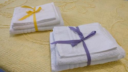 蒙特西尔瓦诺La Casetta的两张白色毛巾,桌子上有紫色的弓