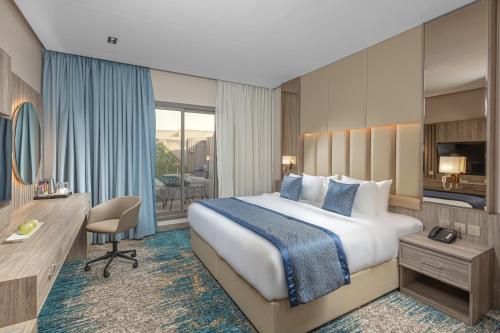 利雅德Seven Gardens Hotel的酒店客房设有一张大床和一张书桌。