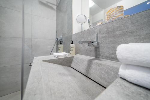 林道bodenseezeit Apartmenthotel Garni的浴室配有盥洗盆、淋浴和毛巾
