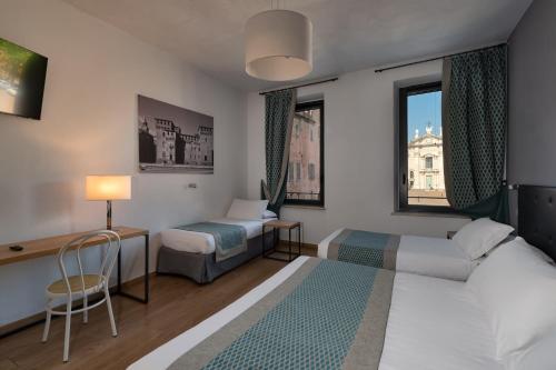 曼托瓦Hotel dei Gonzaga的酒店客房带一张床、一张桌子、一张床和窗户。