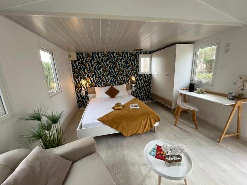 托尔雷莱Camping Le Calypso 5 étoiles的一间卧室配有一张床、一张沙发和一张桌子