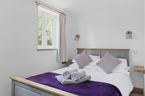 OakamoorLuxurious Barn Conversion的一间卧室配有带毛巾的床和窗户。