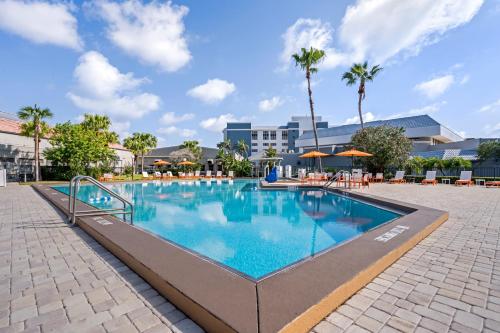 奥兰多Holiday Inn Orlando International Drive - ICON Park的度假村的游泳池,配有桌子和遮阳伞