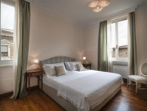 锡耶纳La Villa的卧室设有一张白色大床和两个窗户。