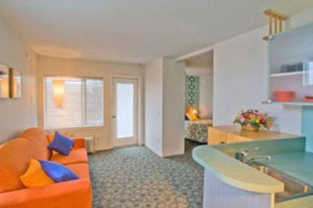 怀尔德伍德斯达鲁斯酒店的一间带橙色沙发的客厅和一间厨房