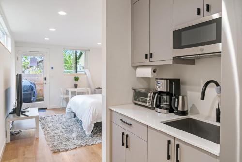 西雅图Modern apartment near light rail的一间带白色橱柜和水槽的厨房以及一间卧室