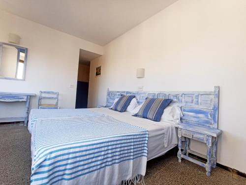 罗列特海岸圣安娜旅舍的一间卧室配有两张带蓝白色床单的床