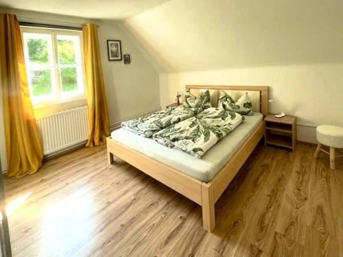 费尔德基兴Lendorfer Cottage的一间卧室配有一张铺有木地板的床和窗户。