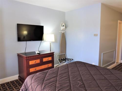 格罗顿温莎汽车旅馆的一间卧室配有一张床、一台电视和一个梳妆台