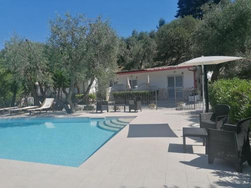 佩斯基奇Agriturismo Valle Dei Gelsi的房屋旁的游泳池配有椅子和遮阳伞