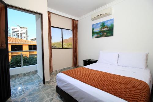 圣玛尔塔Hotel Rodadero Inn By GEH Suites的一间卧室设有一张床和一个大窗户