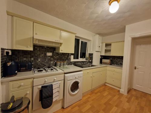 KentSwanley Guest House的厨房配有白色橱柜和一台洗衣机