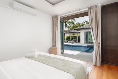 邦涛海滩Tropical villa within 5 minutes walk to Bangtao Beach的一间带大床的卧室和一个游泳池