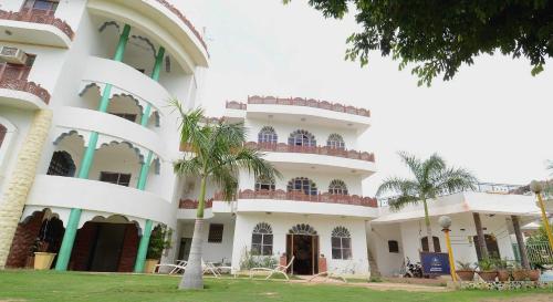 焦特布尔OYO Flagship Ranibagh Palace的一座白色的大建筑,前面有棕榈树