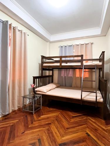 碧瑶Cozy Millenium House的客房设有两张双层床,铺有木地板。