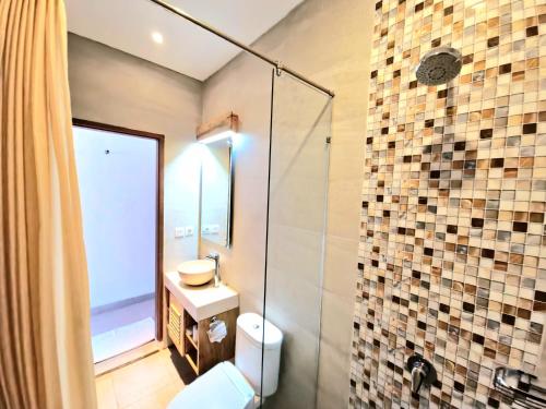 库塔Kamandaka的一间带卫生间和玻璃淋浴间的浴室