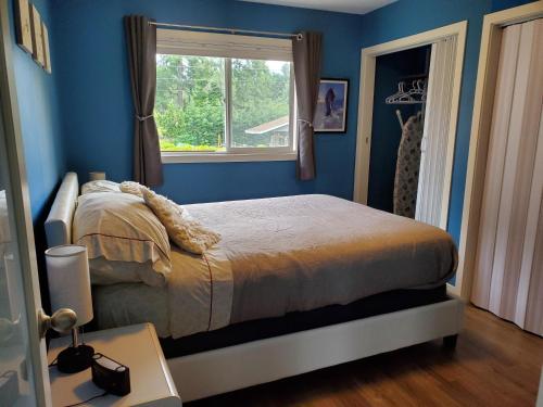 Oyster BaySaratoga beach cottage, private non-resort, easy beach access, 35mins Mt Washington的一间卧室设有蓝色的墙壁和一张带窗户的床