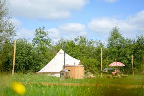 Minicamping de dobbe的大型白色帐篷,配有野餐桌和坐在前面的一名妇女