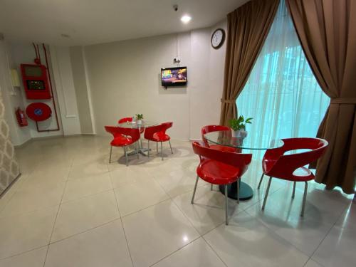 马六甲Sweet Memories Hotel的一间用餐室,配有红色椅子和玻璃桌