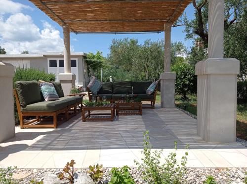 鲁巴达My Mediterranean Villa with Huge Garden and own Parking的一个带沙发和椅子的庭院,位于木制凉棚下