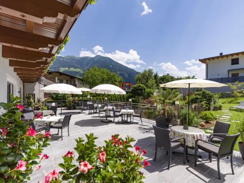 菲根Hotel Landhaus Zillertal的一个带桌椅和遮阳伞的庭院