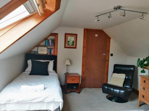 卡伦德Nest Holiday Home Central Callander, Trossachs Self-catering的阁楼卧室配有1张床和1把椅子