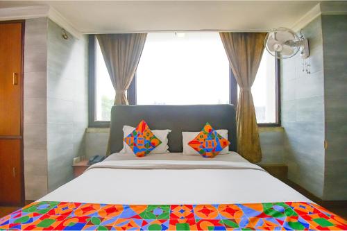 SaluaFabHotel Raj Darbar的一间卧室配有一张带色彩缤纷枕头的大床